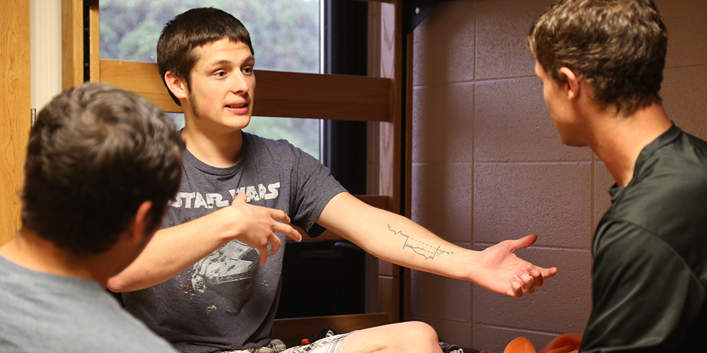 Nathan Ressler shows his tattoo of the Heilsgeschicte (salvation history), the cornerstone of the Hesston College’s Biblical Literature class. – Alex Leff/ Hesston College
