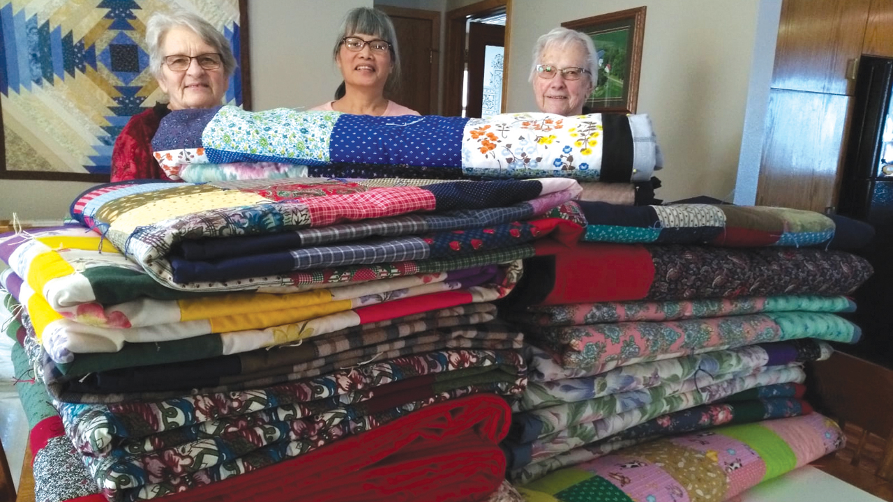 Eva Harder, left, completed her 100th comforter for Mennonite Central Committee on Aug. 19. Here she is joined by two women from First Mennonite Church in Mountain Lake, Minn., who helped tie some of the comforters, Pratoomporn Harder and Erna Johnson (who recently turned 84 and has made more than 30 comforters for MCC this year). — Gordon Harder