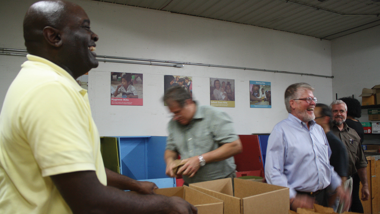 The mood was jovial as former MCC U.S. board member Leonard Dow, left, helped pack prisoner care kits in 2017 at the MCC East Coast Material Resources Center in Ephrata, Pa. Dow, other MCC U.S. board members and MCC staff, including MCC U.S. executive director J Ron Byler, right foreground, packed 100 kits of personal items for people who were incarcerated or who were participating in re-entry ministries after leaving prison in the greater Philadelphia area. — Jill Steinmetz/MCC