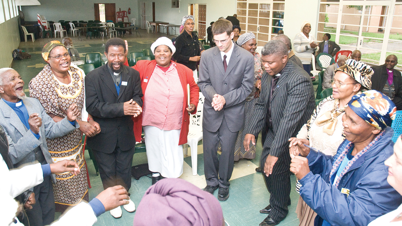 Amos Sobambela, M.N. Madikane, E.S. Simanga, Olga N.N. Dubula, Joe Sawatzky, Reuben Mgodeli, Mavis Tshandu, Miriam Nompumelelo Dokolwana and Anna Sawatzky sing and dance at Bethany Bible School in May 2009 in Mthatha, South Africa. — Ryan Miller/MMN