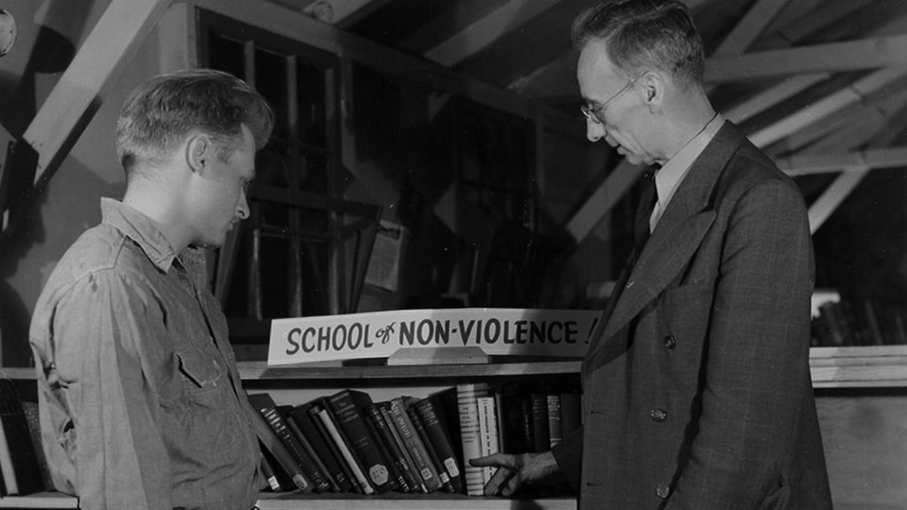 A.J. Muste, right, a leading Protestant pacifist clergyman and frequent visitor to CPS camps, inspects a collection of books on peace and nonviolence at Camp No. 52 in Powellsville, Md. — Center on Conscience and War Records, Swarthmore College Peace Collection