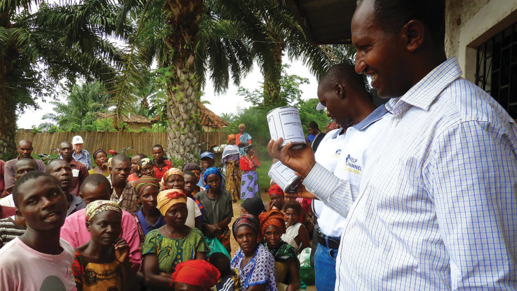 Cassien Ndikuriyo, director of MCC partner Help Channel Burundi, speaks at a distribution of MCC canned turkey in Burundi in 2014. Ndikuriyo had previously visited the MCC Material Resources Center in Ephrata, Pa., and so was able to share about the journey of the canned meat and the story of the people who made it possible. — Paul Mosley/MCC