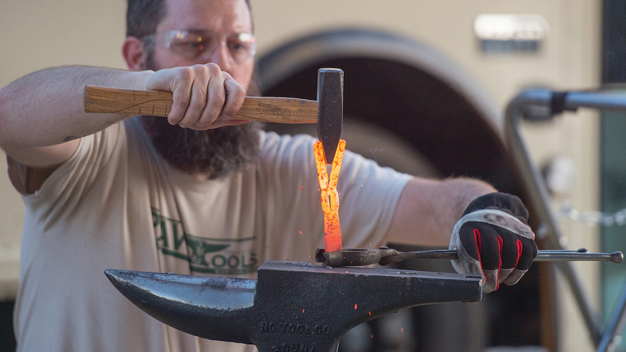 Michael Martin, founder and executive director of RAWtools, forms the metal of what used to be a gun into a hand-held garden tool in 2019 at Hesston College. — Larry Bartel/Hesston College