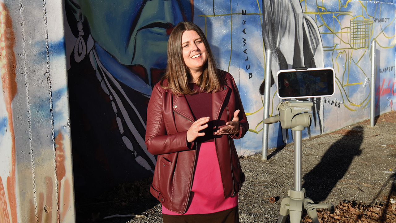 Ruth Harder, pastor of Rainbow Mennonite Church in Kansas City, Kan., records a video sermon in front of the 42nd Street Mural, a project of the Rosedale Development Association and local artists to preserve the history of the Rosedale area. — Jesse Graber