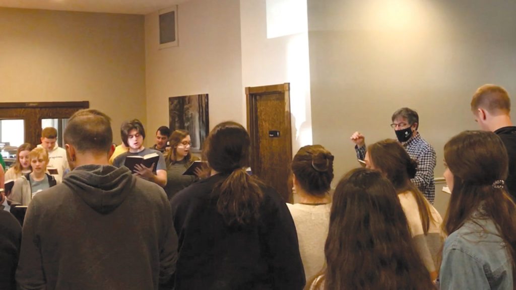 Students sing “Gott ist die Liebe” March 5 at Rosedale Bible College in Ohio. Song leader Ken Miller is masked, as part of Rosedale policy for staff interacting with students who have tested negative and are committed to staying within the campus “sanctuary bubble.” — Rosedale Bible College