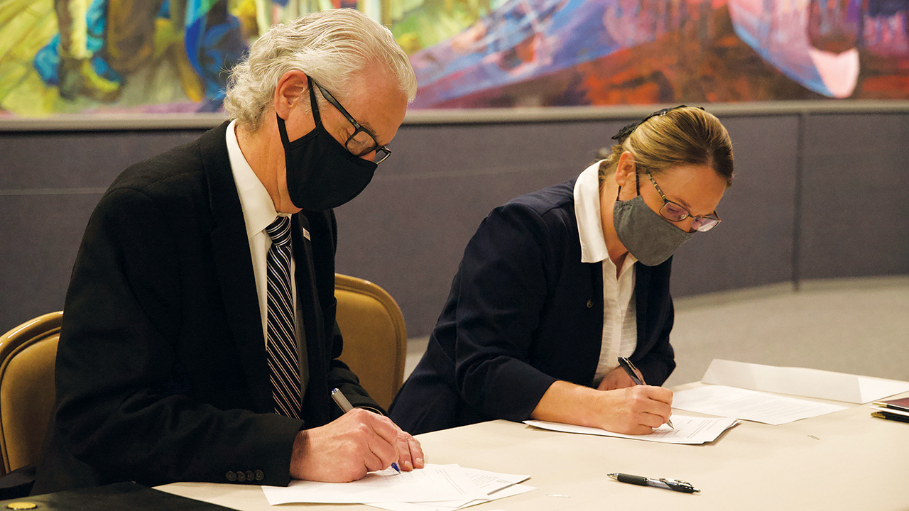 Malone University President David King, left, and Zollikon Institute director Norita Yoder sign an agreement about Zollikon Institute on March 17 at the Amish and Mennonite Heritage Center in Berlin, Ohio. — Malone University