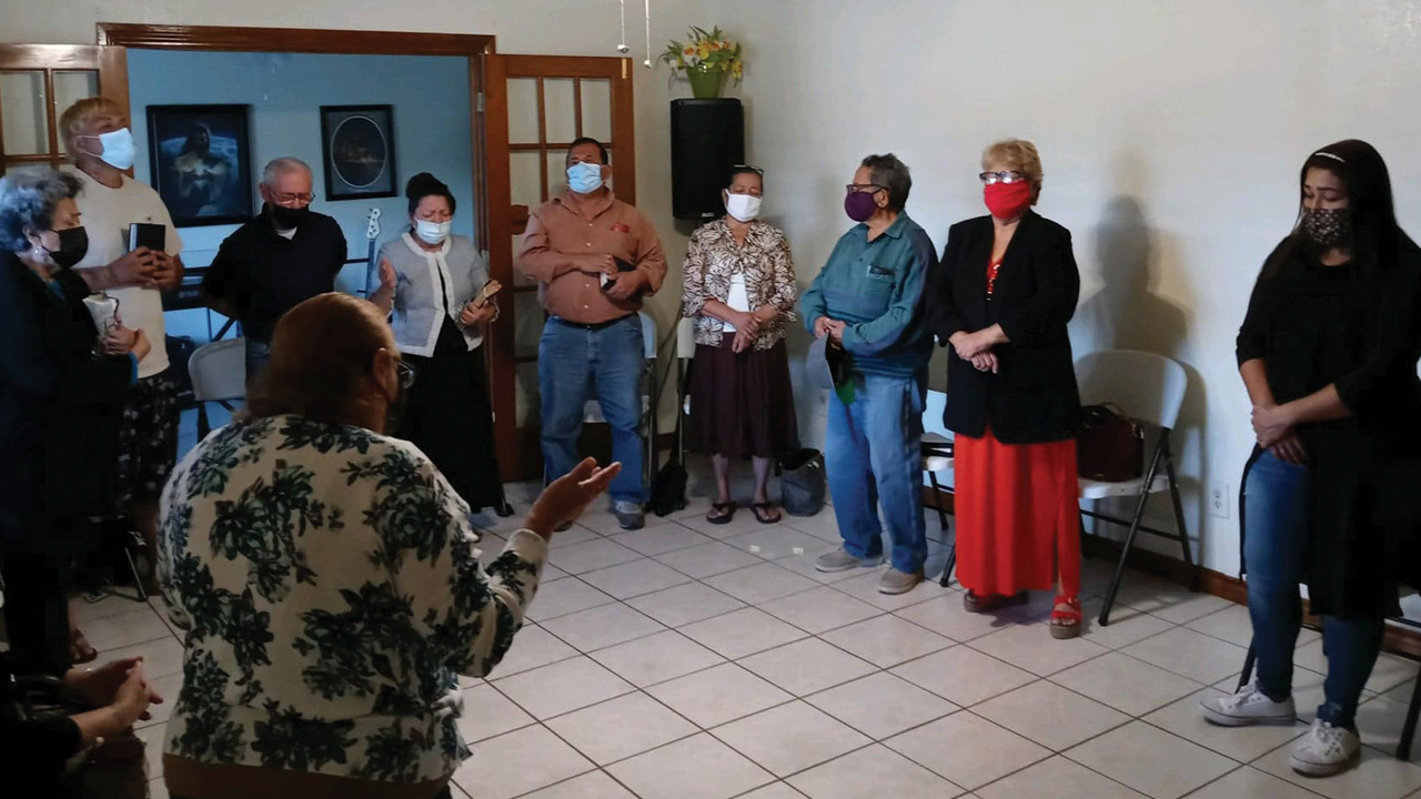 Nuevo Amanecer Pastor Nena Bennett, in doorway, leads a prayer April 19 in her home in Brownsville, Texas. The gathering was one of the church’s first in more than a year. — Nena Bennett