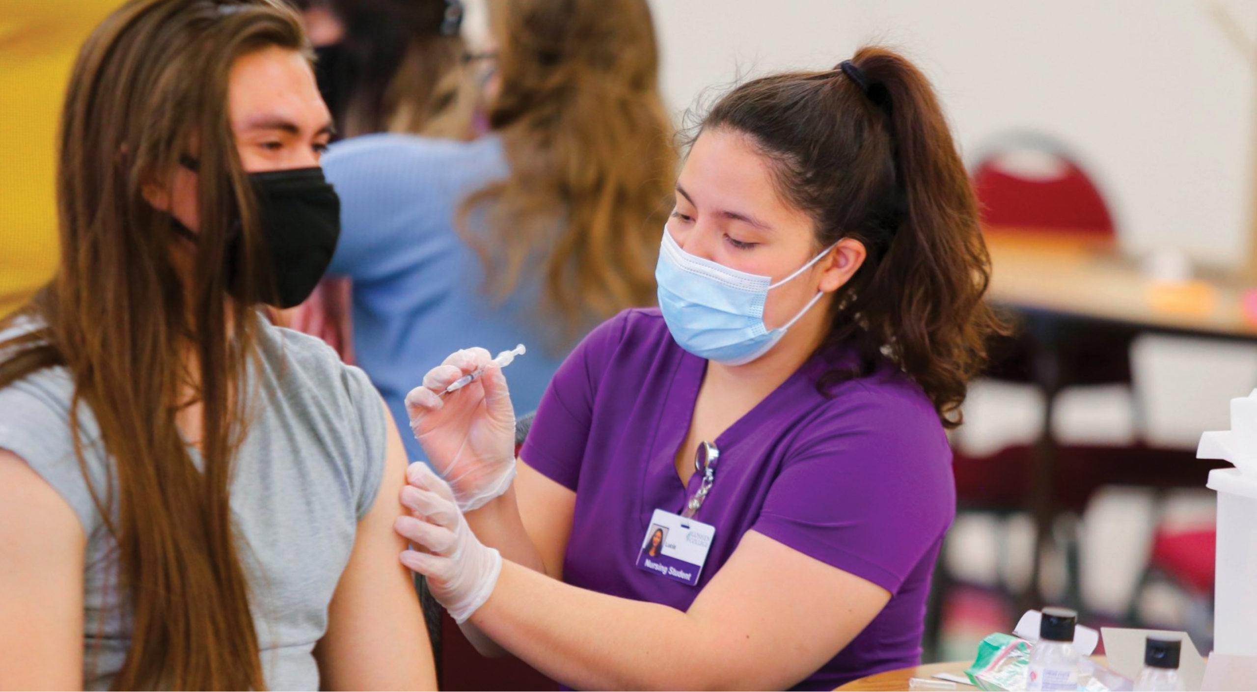 Lucia Keim Martinez, a senior Goshen College nursing major from Goshen, Ind., administers a vaccine shot to Khampha Stempel, a senior from Broadway, Va. — Goshen College