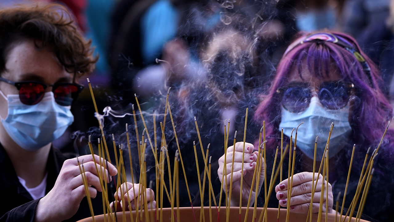 People leave incense sticks in a pot of rice to honor the victims of the Atlanta area massage parlors shootings during a memorial in Kansas City, Mo., March 28. The March 17 shootings at three Georgia massage parlors and spas that left eight people dead, six of them women of Asian descent, come on the heels of a recent wave of attacks against Asian Americans. Photo: Charlie Riedel/AP