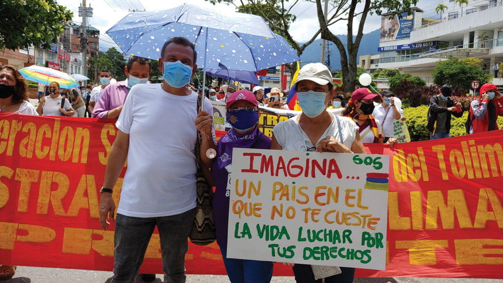 Daniel Vargas, Pastor Amanda Valencia and Gloria Bastidas of the Mennonite Church of Mennonite Church of Ibagué march with the Human Rights Defense Committee of Tolima. The sign says, “Imagine . . . a country where your life is not at risk when fighting for your rights. — Mennonite Church of Ibagué