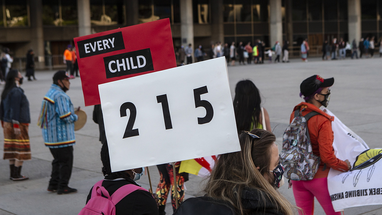 People form a circle during a vigil in Toronto on May 30 for the 215 Indigenous children whose remains were uncovered on the grounds of a former residential school near Kamloops, B.C. The discovery of a mass grave was announced late May 27 by the Tk'emlups te Secwépemc people after the site was examined by a team using ground-penetrating radar. — Chris Young/The Canadian Press via AP