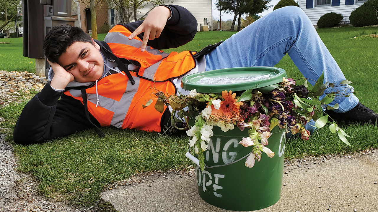Jovan (identified only by his first name at his family’s request) enjoys his work of weekly curbside food scrap pickup with a particularly attractive bucket. — Daniel Yoder