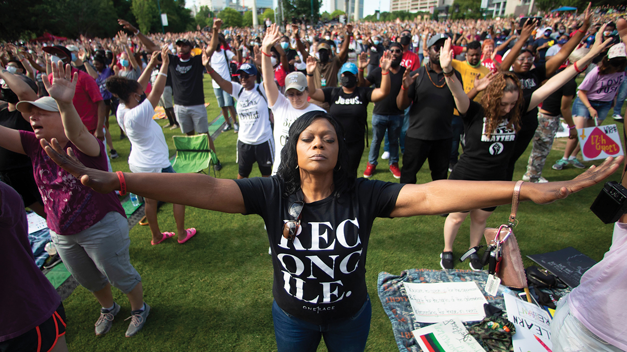 A woman prays during a Juneteenth event hosted by OneRace Movement, a religious organization, at Atlanta’s Centennial Olympic Park on June 19, 2020. — John Bazemore/AP