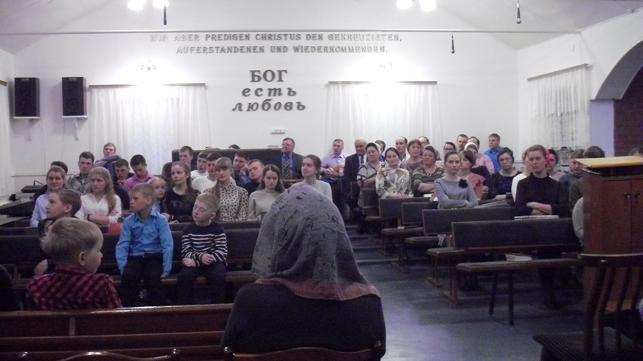 Worshipers attend a service April 20 at the Mennonite Brethren church in Solntsevka, a community about 20 miles south of Apollonovka. The text on the wall reads “God is love.” — William Yoder