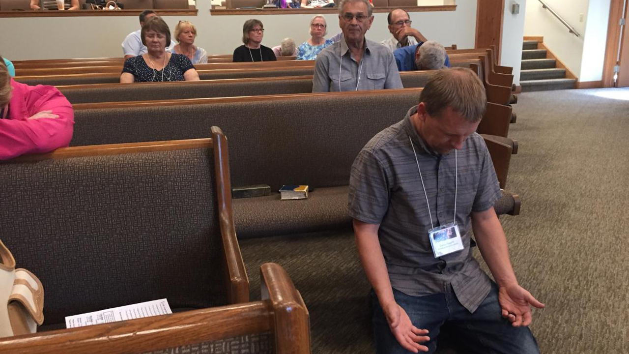 Delegate Corey Regehr prays during the South Central Mennonite Conference assembly July 24 in Hesston, Kan. — Paul Schrag/AW