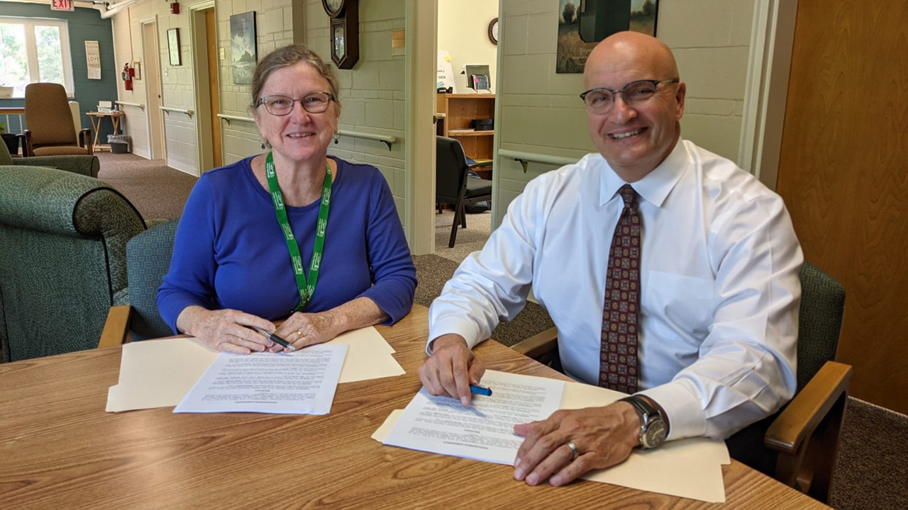 Mennonite Home Communities of Ohio board chair Elizabeth Kelly and John Warner, president and CEO of Brethren Retirement Community, sign management agreement documents. — Mennonite Home Communities of Ohio