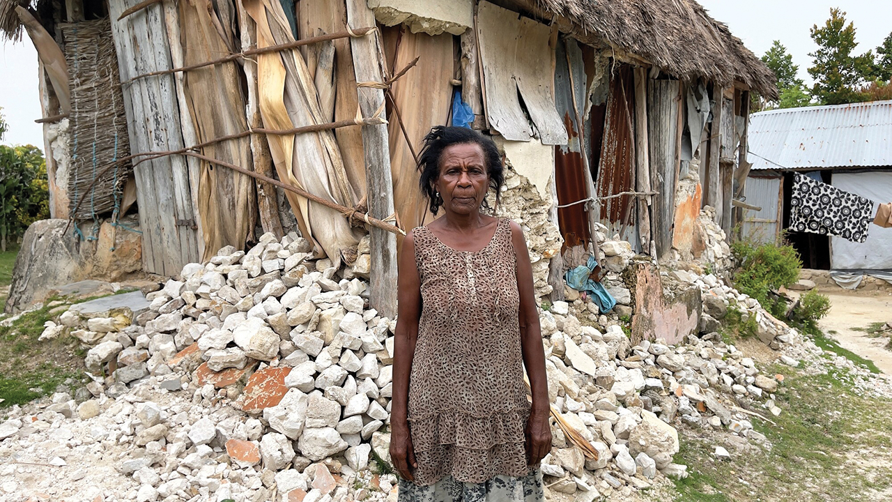 Prescione Roger stands in front of her home, which was destroyed by an earthquake in Saint-Jean-de-Sud, Haiti. — Paul Shetler Fast/MCC