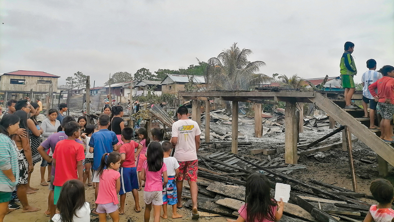 Adults and children on Isla Iquitos in Peru survey the damage at the site where their church and five houses burned to the ground Aug. 29. Children stand on the stairs that once led to their space for worship and learning. — Juan Carlos Moreno/MMN