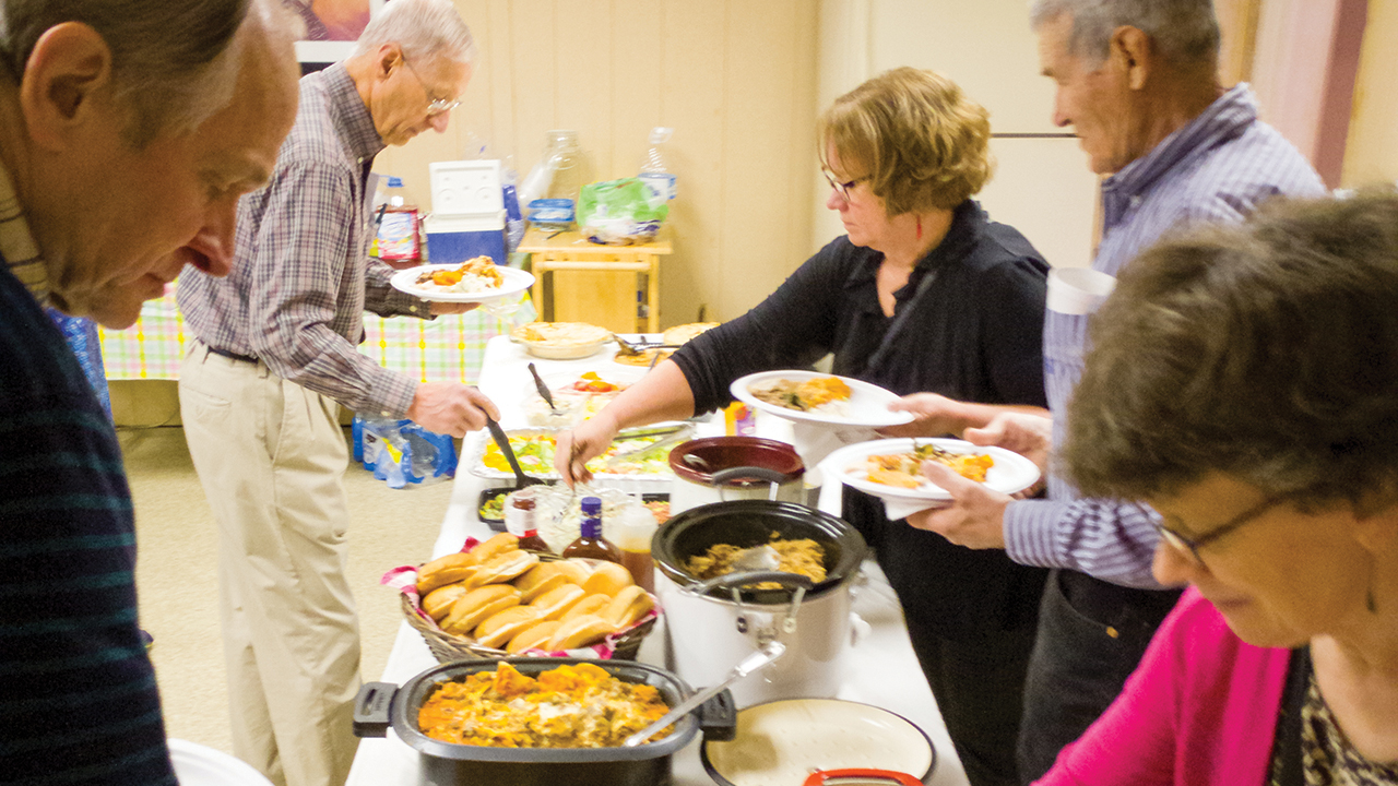 Mississippi Service-Learning Tour participants Steve Schmid, Merlin Grieser, Arloa Bontrager (tour leader), Gerald Freyenberger and Carol Sandbakken dig into a Sunday potluck at Open Door Mennonite Church in Jackson, Miss., on March 8, 2020. — Travis Duerksen/MMN