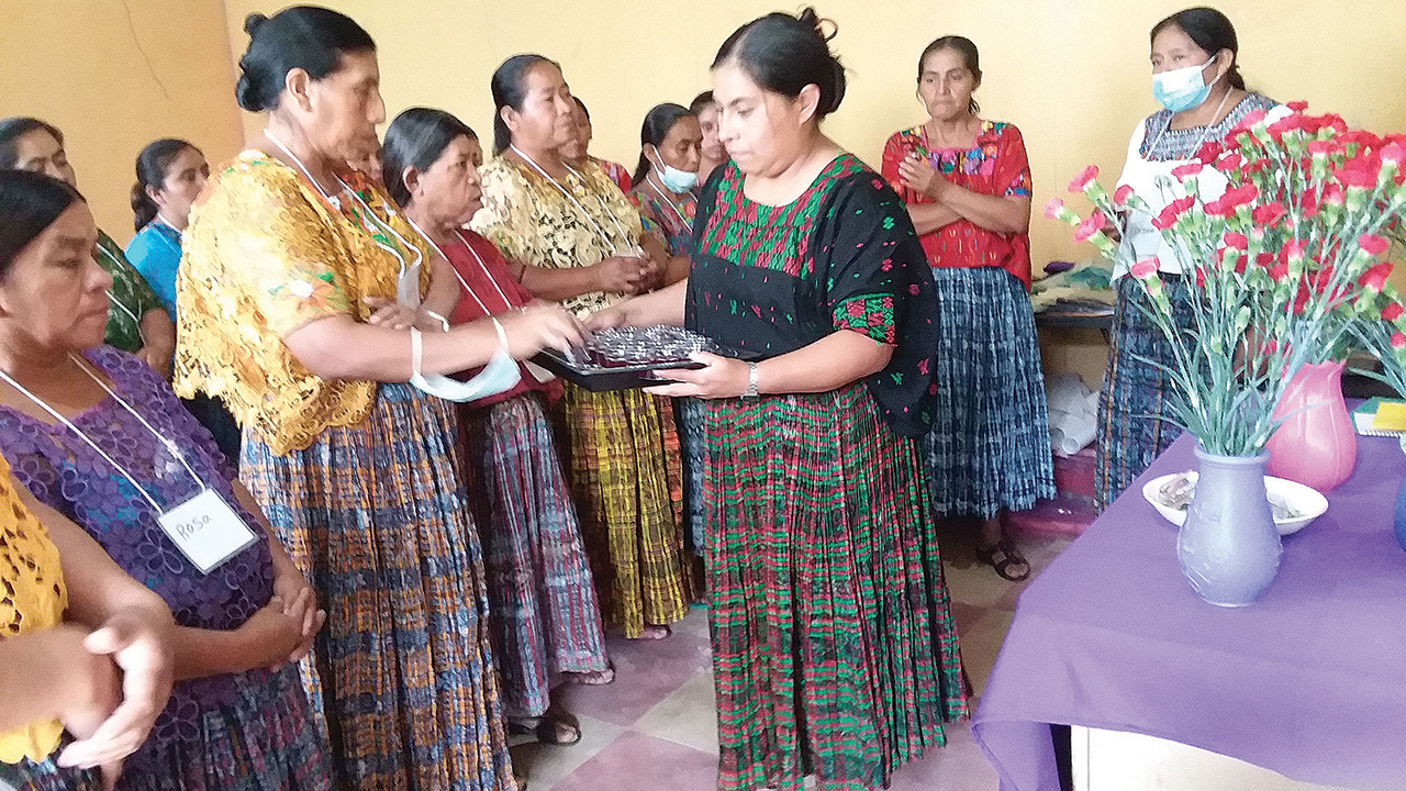 Small group leader Maria Elena Caal serves communion to Lucia Cuc Caal as a part of closing worship at the Kekchi trauma healing workshop July 27-28 in San Pedro Carchá, Guatemala. Observing are two other group leaders on the far right, Maria Pa Bol and Petrona Caz Xo. — Deb Byler/MMN