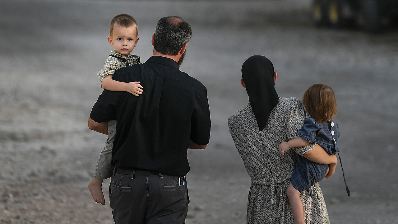 A man and a woman hold children as they walk on the grounds of the Christian Aid Ministries headquarters in Titanyen, Haiti, on Oct. 21. Seventeen members of CAM have been kidnapped. — Matias Delacroix/AP