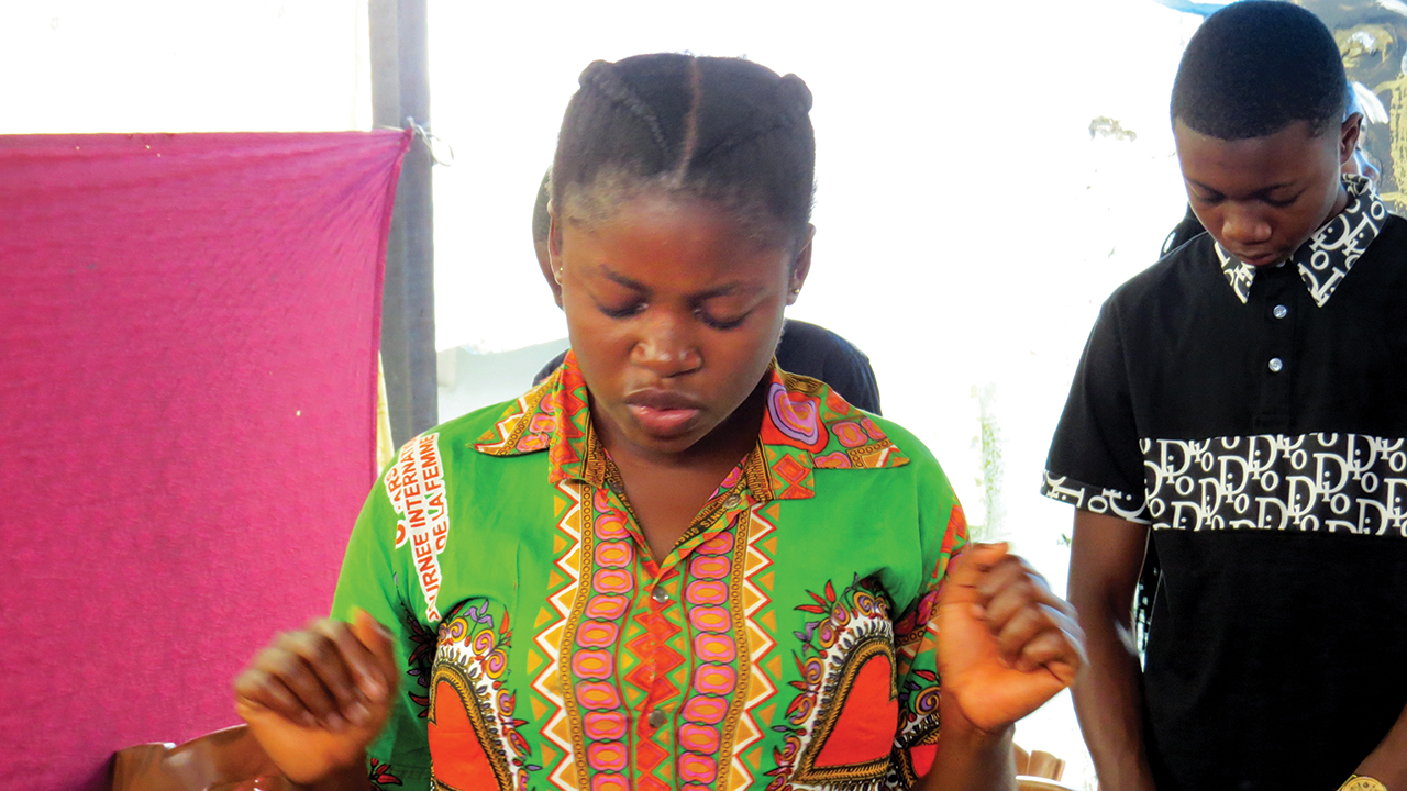 Jeanne Kobamusu enters into the spirit of worship with her Nouvelle Alliance congregation in Kinshasa, Democratic Republic of Congo. The congregation is a member of Congo Mennonite Church. — Lynda Hollinger-Janzen/MMN
