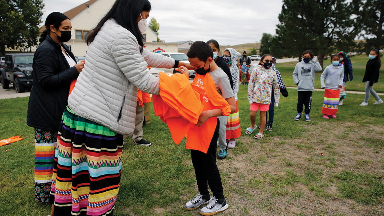 Students at Red Cloud Indian School wait in line to receive orange T-shirts on Sept. 30 in Pine Ridge, S.D. Students and teachers wore orange in solidarity with Indigenous children of past generations. — Emily Leshner/AP