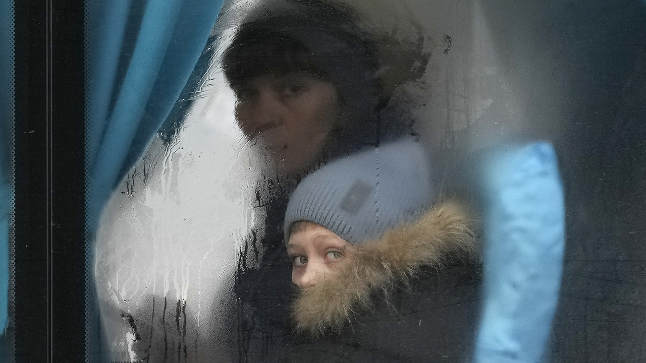 A woman and child peer out of the window of a bus as they leave Sievierodonetsk, the Luhansk region, eastern Ukraine, Feb. 24. — Vadim Ghirda/AP