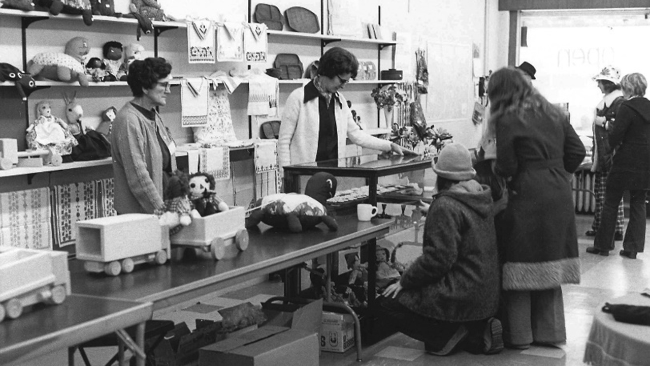 College students check out the Selfhelp Crafts (now Ten Thousand Villages) display at the Et Cetera Shop in Bluffton, Ohio, on opening day, Jan. 18, 1974. Sales staff Celia Hilty and store manager Lois Kreider stand behind the counter. — Leland Gerber/MCC