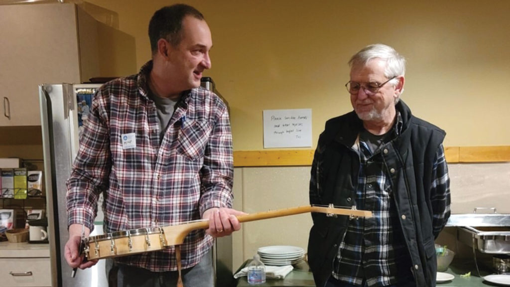Mike Davis presents the repaired banjo to Wesley Emmelot. — MDS Canada