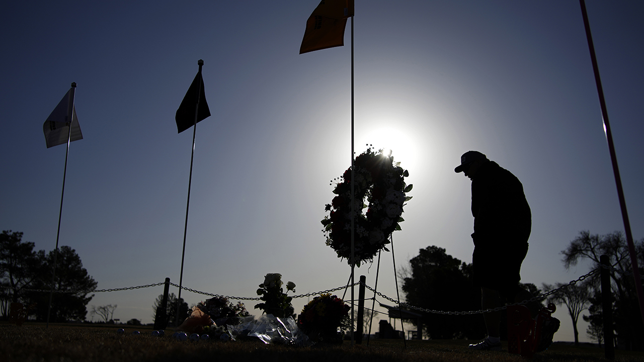 A golfer visits a makeshift memorial at the Rockwind Community Links on March 17 in Hobbs, N.M. The memorial was for student golfers and the coach of University of the Southwest killed in a crash in Texas. — John Locher/AP