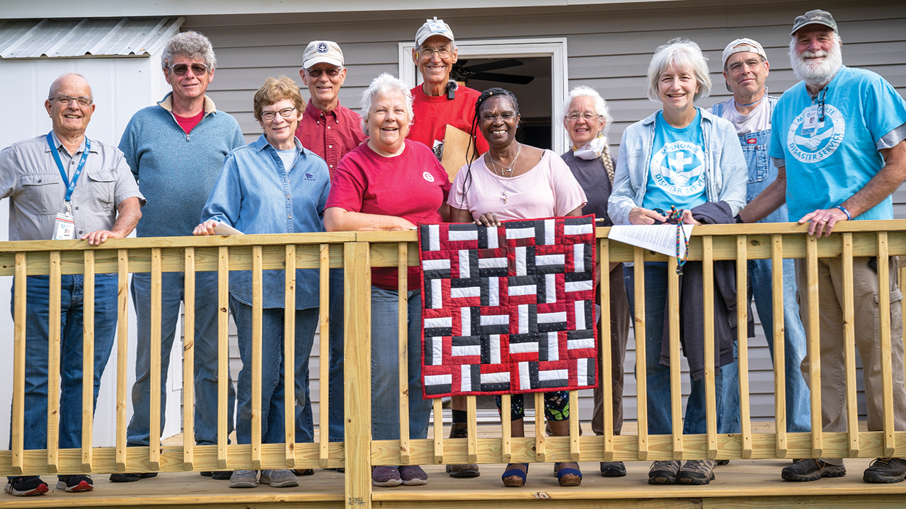 Cynthia Williams and Mennonite Disaster Service volunteers celebrate the dedication of her home in April in Marianna, Fla. Below: MDS volunteers Millie Hershey, right, of Lancaster, Pa., and Ed Basinger of Hesston, Kan., work on a house. — Paul Hunt/MDS
