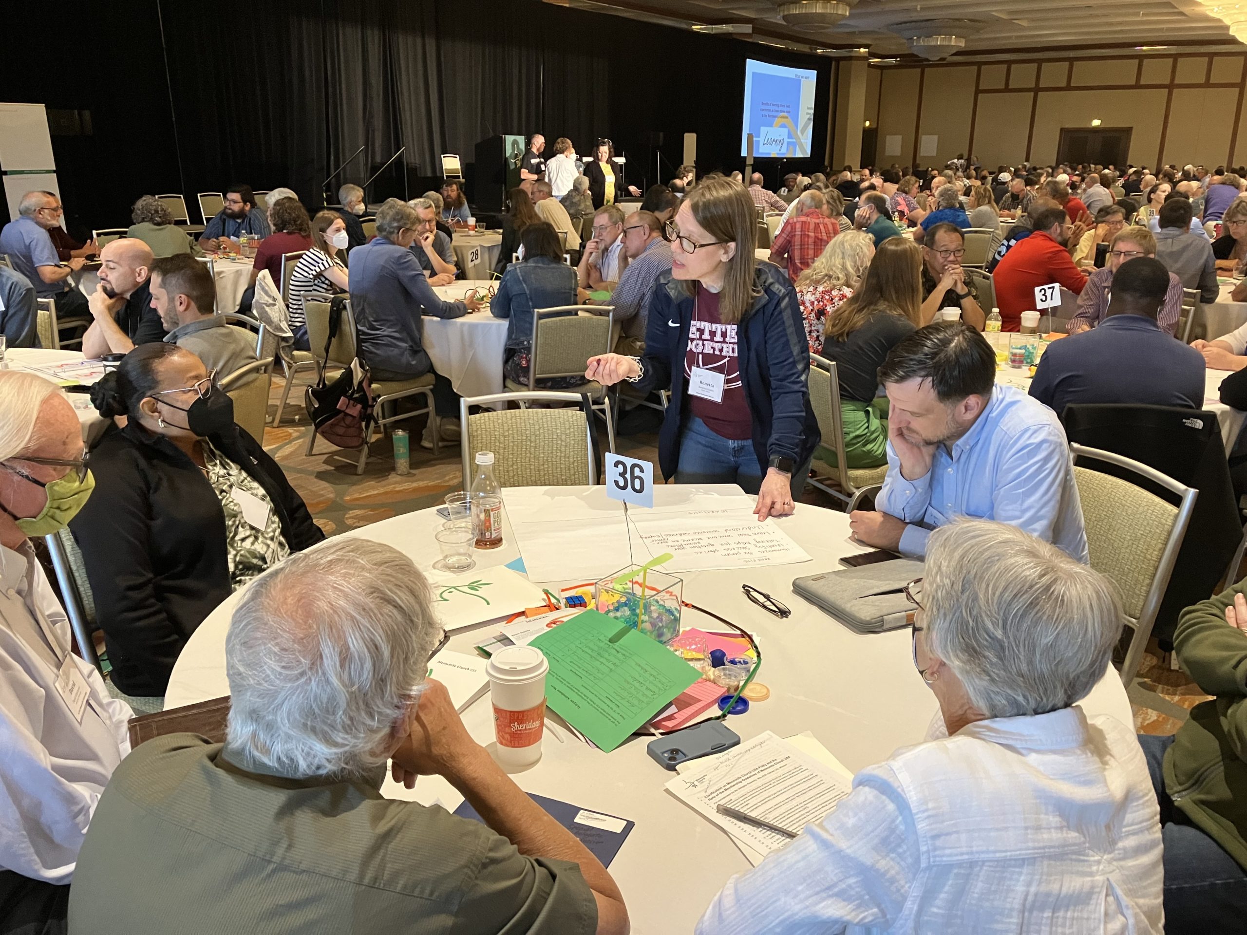 Renetta Gooden of Hope Mennonite Church in Wichita, Kan., (standing) takes part in table discussion during the Mennonite Church USA special delegate assembly on May 28. — Photo: Paul Schrag/AW
