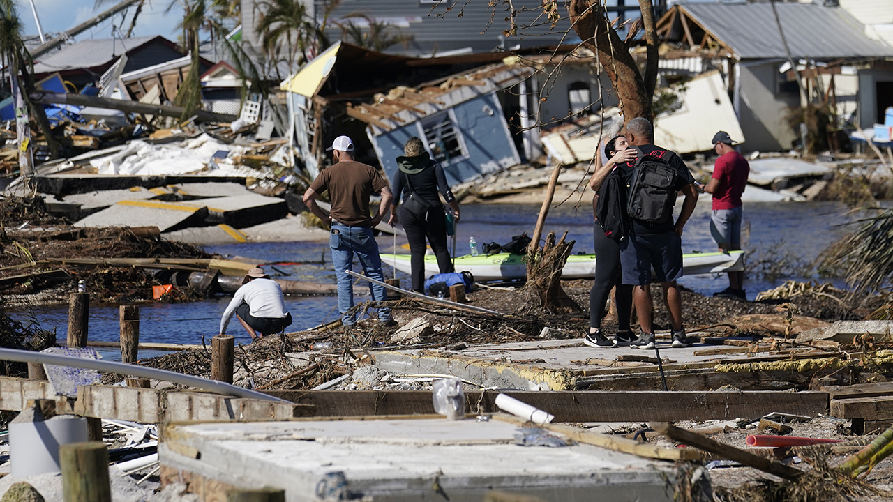 People stand on the destroyed bridge to Pine Island as they view Hurricane Ian damage Oct. 2 in Matlacha, Fla. The only bridge to the island is heavily damaged so it can only be reached by boat or air. — Gerald Herbert/AP