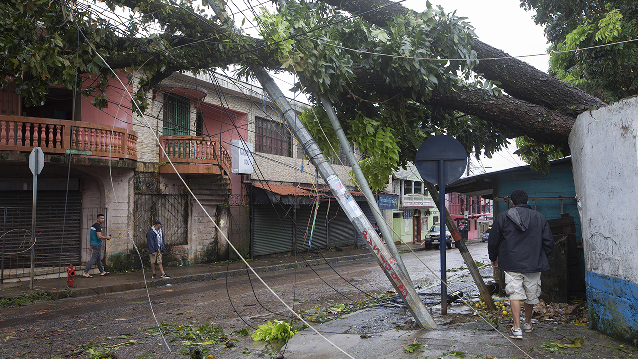 Residents walk under electrical poles broken by the winds of Hurricane Julia in Bluefields, Nicaragua, Oct. 9. — Inti Ocon/AP