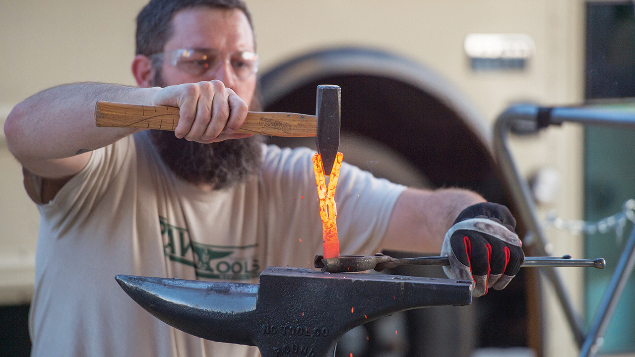 Michael Martin, founder of RAWtools, forms the metal of what used to be a gun into a garden tool in 2019 at Hesston College. — Larry Bartel/Hesston College