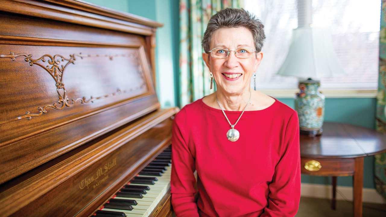 Kathie Weaver Kurtz with the Lehman family’s piano, which now sits in the President's Reception Room at Eastern Mennonite University. — Macson McGuigan/EMU