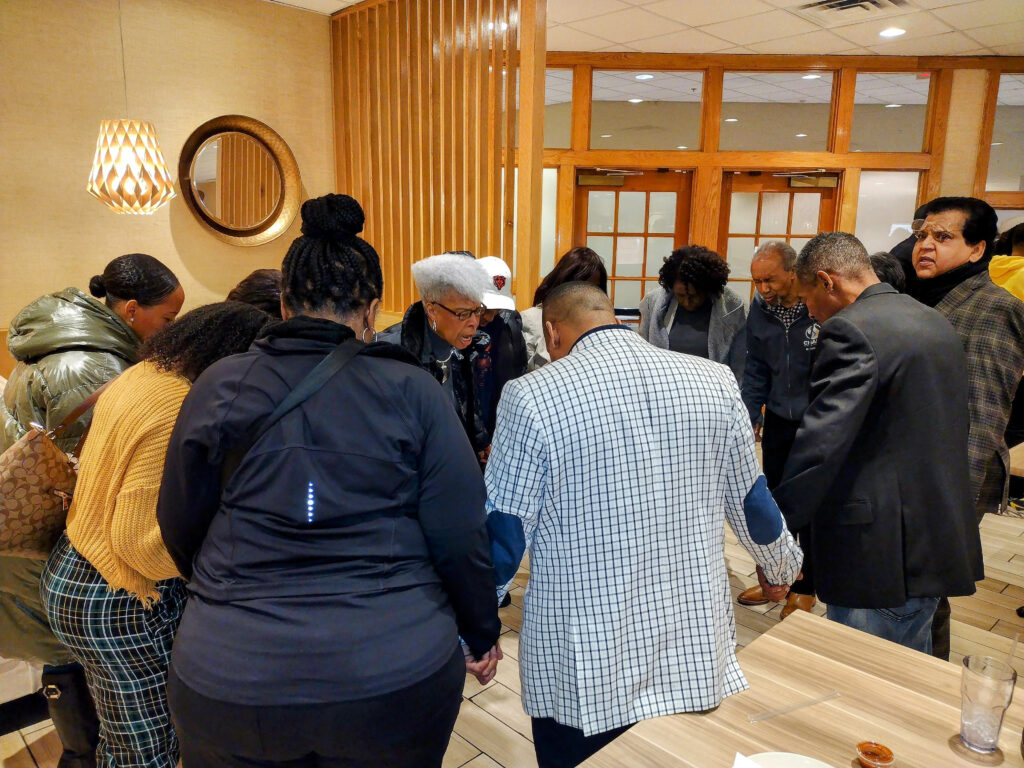 Community members pray in January for a candidate running for alderman who disapproves of offering land reserved for public housing to private interests. — Bethel Community Mennonite Church