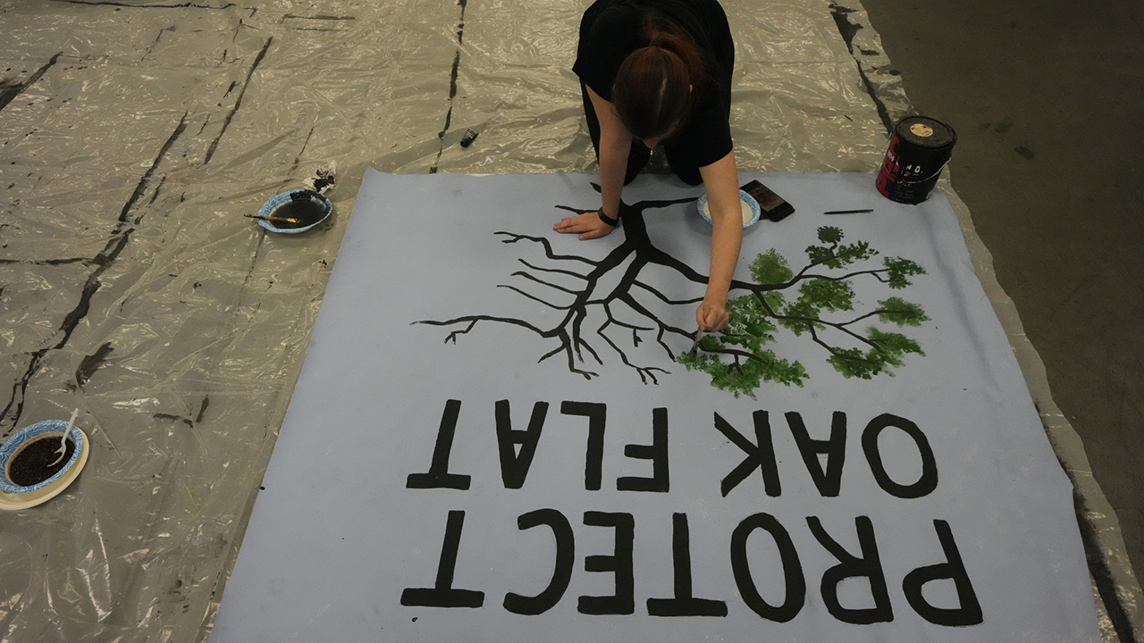 A member of the Apache Stronghold group who traveled from Arizona paints a protest banner March 20 at Self Help Graphics & Art in Los Angeles. — Damian Dovarganes/AP