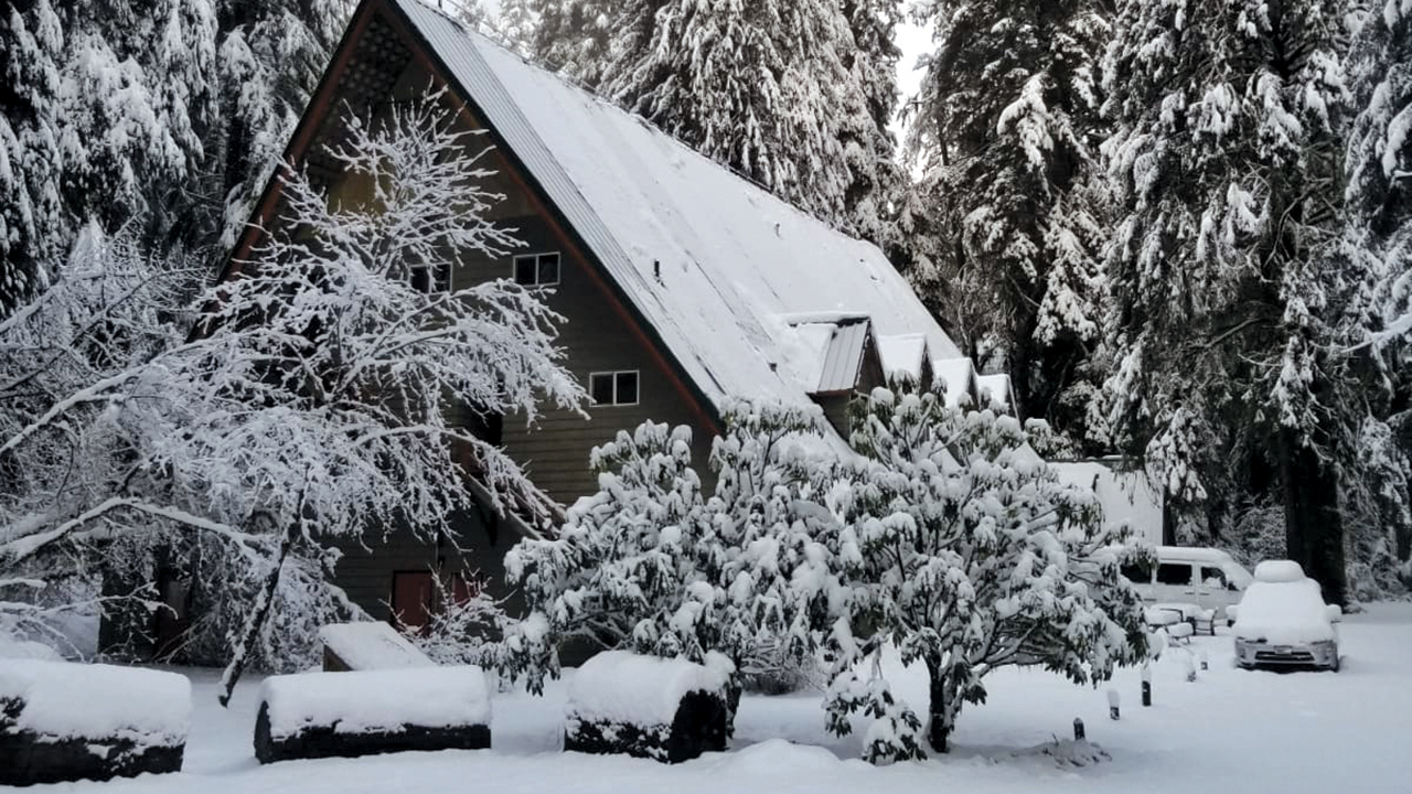 The Drift Creek Camp lodge and vehicles sit under snow in February. — Levi Ebersole