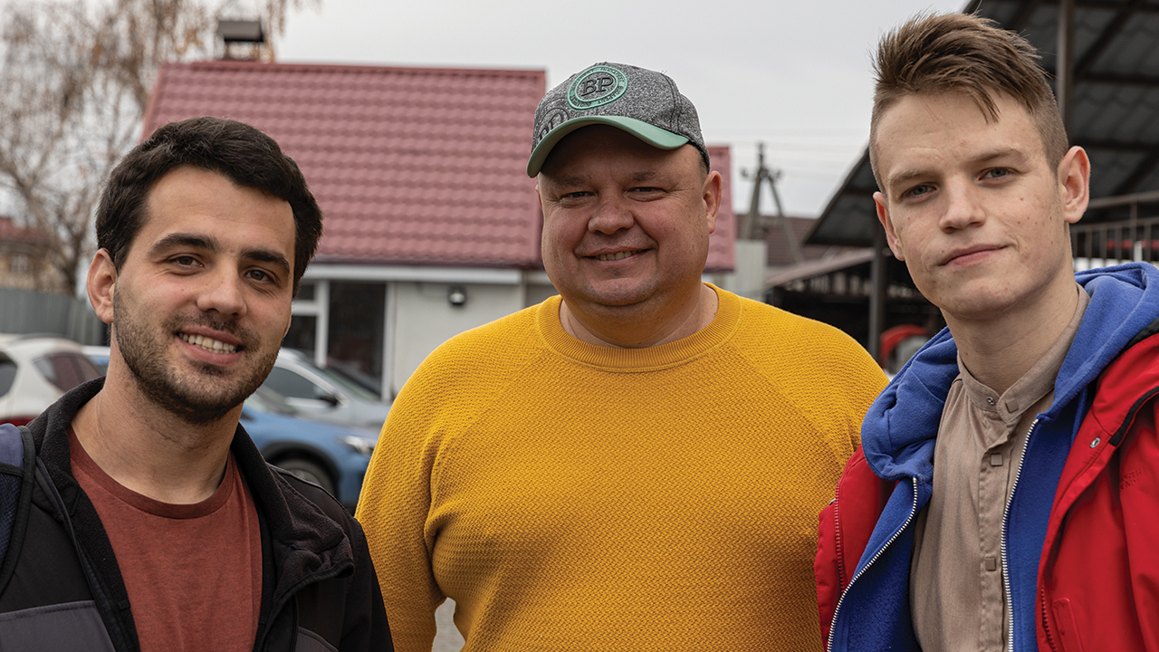 Association of Mennonite Brethren Churches of Ukraine personnel — from left, Rostik, a volunteer; Roman, director; and Andriy, humanitarian coordinator — stand outside a Ukrainian shelter that is supported by Mennonite Central Committee. — Emily Loewen/MCC
