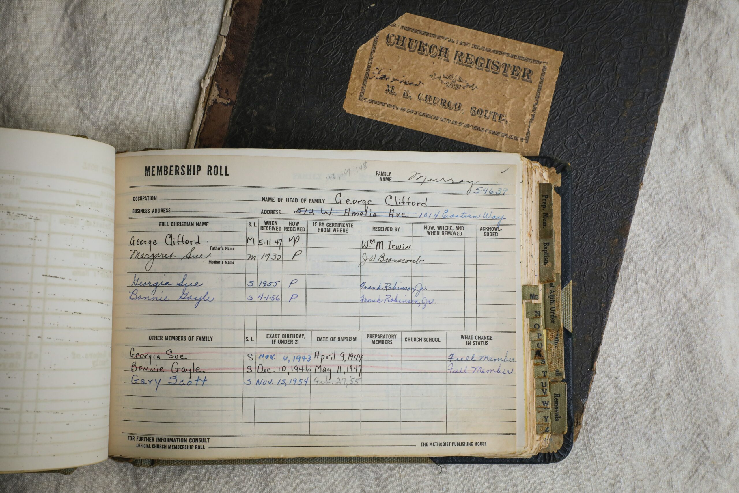 Open vintage membership book in front of a brown church register book