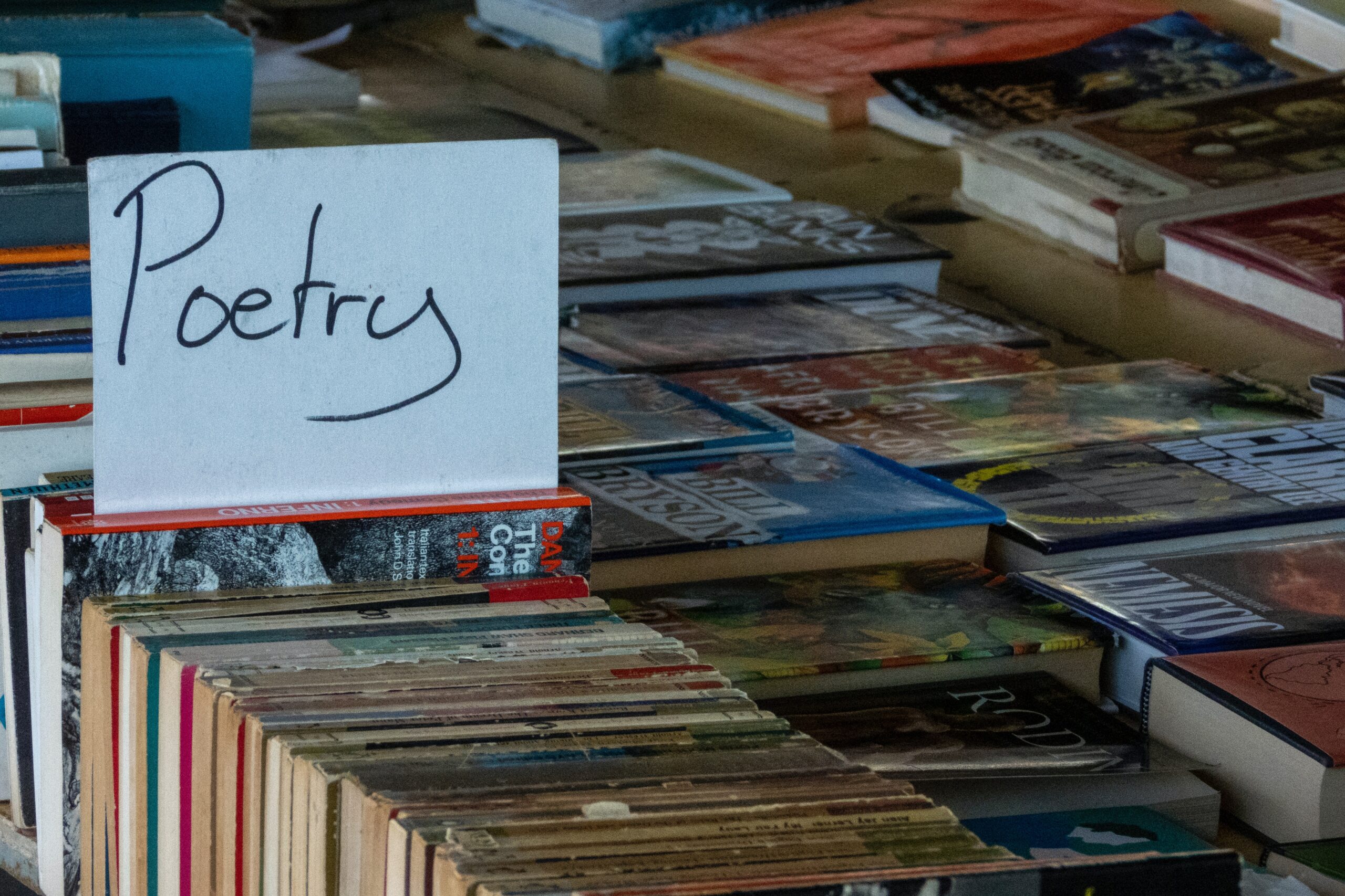 A row of books with a white paper sign that says, "Poetry."