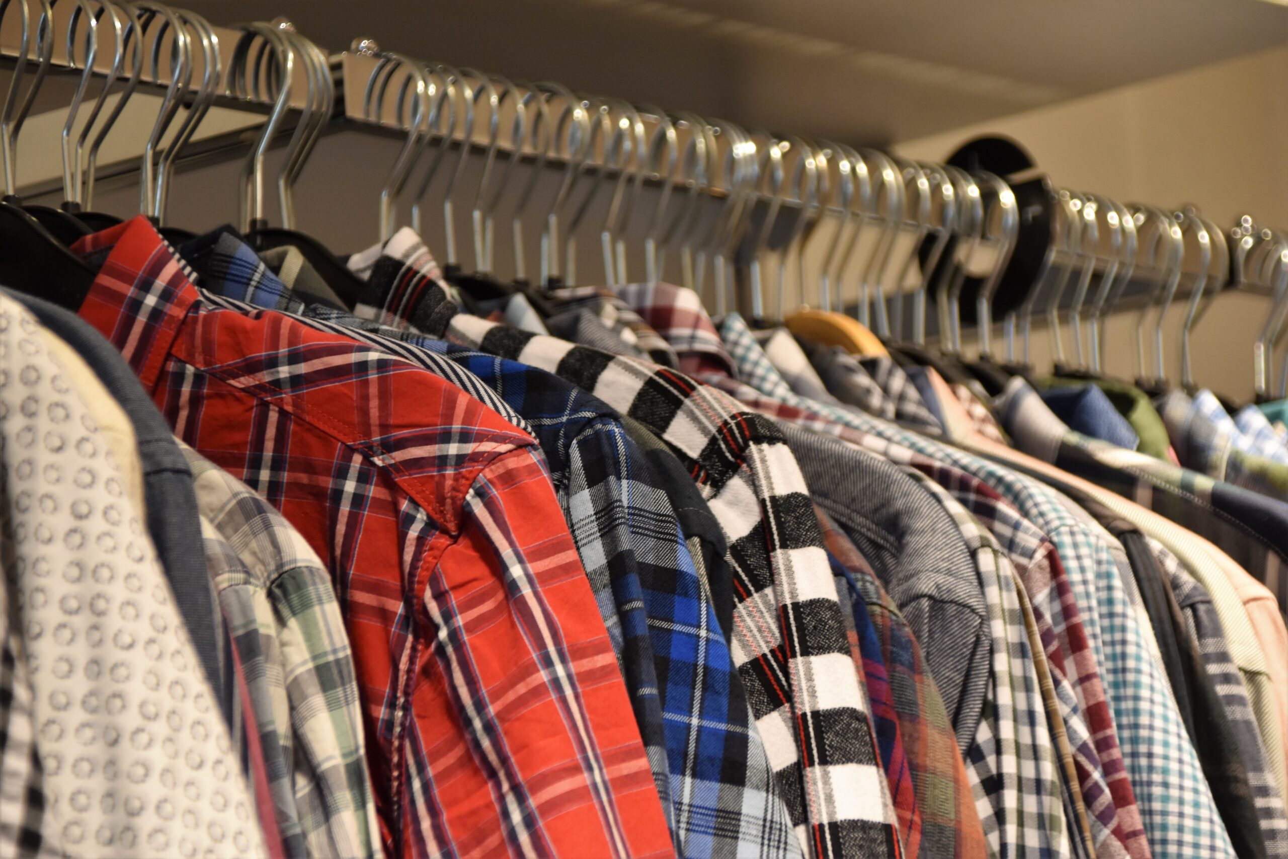 A silver rack with men's plaid shirts on hangers.