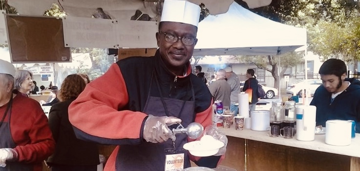 African man wearing white chef's hat scooping ice cream into a bowl.