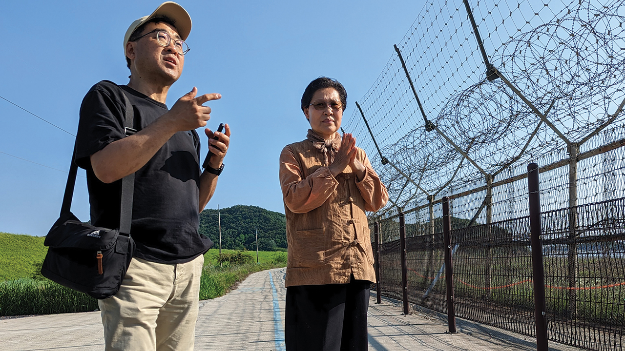 Mennonite Central Committee Northeast Asia representative SeongHan Kim, left, and Gyodong Island peace worker Kim Young-Ae on the South Korean island’s shore, about a mile from North Korea. The blue line is a peace pilgrimage route that follows the border from coast to coast. — Tim Huber/AW