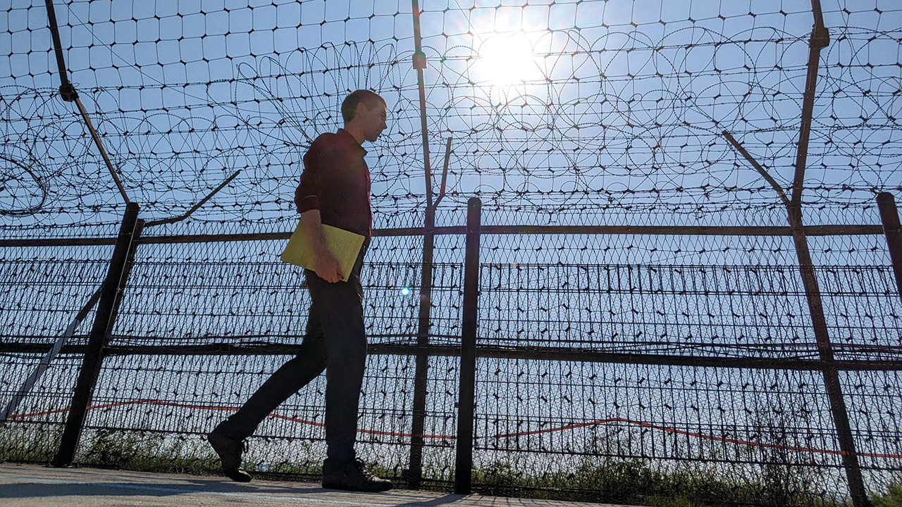 Tim Huber walks along military fencing along the shore of Gyodong Island, South Korea, on June 1. — Tim Huber/AW