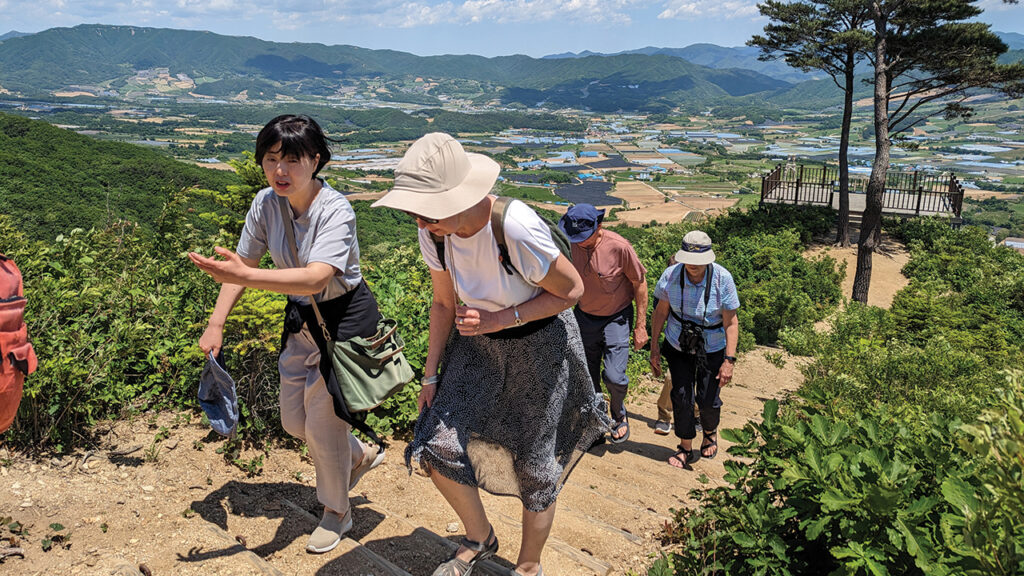 Korean Anabaptist Center director Sun Ju Moon, left, and Mennonite Central Committee Northeast Asia area director Phyllis Mann walk a trail at the Yanggu “punchbowl,” a village surrounded by a circular ridge near the 38th parallel that was the site of fierce fighting during the Korean War. They are followed by MCC U.S. executive director Ann Graber Hershberger and her husband, Jim Hershberger. — Tim Huber/AW