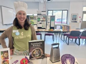 Heather Wolfe, wearing a white chef's hat, poses with her book, "Sustainable Living."