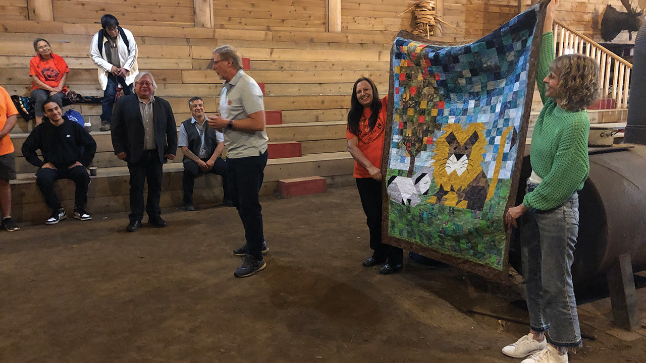 Wayne Bremner, executive director of Mennonite Central Committee British Columbia, presents a quilt to Dalton Silver, chief of Semá:th First Nation. Bridget Findlay and Karen Heidebrecht Thiessen of MCC B.C. hold the quilt. — John Longhurst/AW